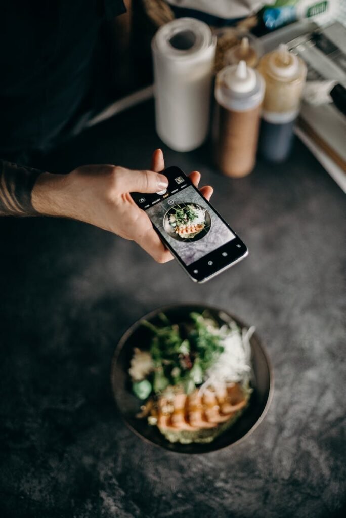 A person photographing a beautifully plated Asian dish with a smartphone camera.